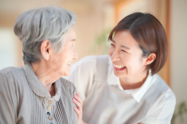 笑い合う女性スタッフと高齢女性